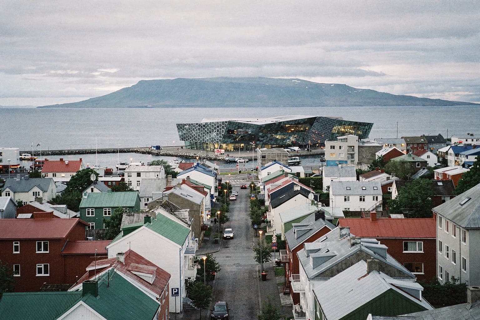 Colourful corrugated-iron roofs of central Reykjavík seen from the Hallgrímskirkja tower, with Mount Esja across the bay